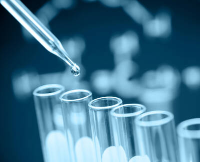 A dropper releasing a liquid droplet into a row of clear test tubes, with a blurred DNA structure in the background.
