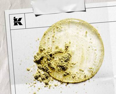 En sirkulaer flekk av lys krem med en strukturert haug av grønt pulver, presentert på et hvitt ark merket med en logo.