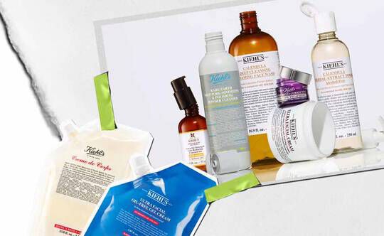 En samling av Kiehl's hudpleieprodukter, inkludert kremer og serum, kunstnerisk arrangert med levende emballasje og synlige etiketter.