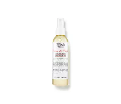 A bottle of Kiehl's Creme de Corps Nourishing Dry Body Oil, featuring a spray nozzle and a clean, minimalist label design.