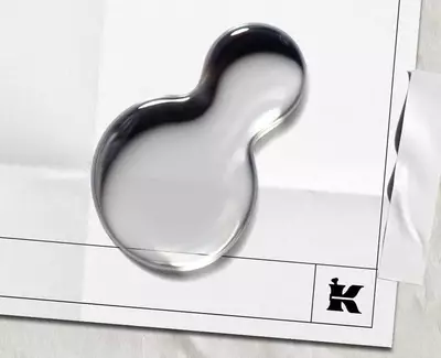 To vanndråper på et blankt ark med en svart "K"-logo og et stykke tape øverst.