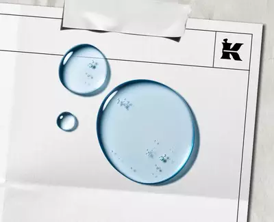 To vanndråper på et blankt ark med en svart "K"-logo og et stykke tape øverst.
