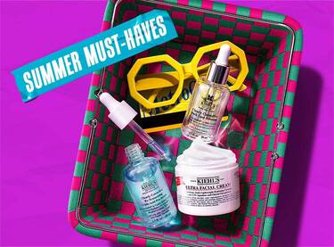 Et lilla banner med en grønn og rosa flettet kurv fylt med Kiehl's hudpleieprodukter og gule solbriller, med blå teip der det står 'SUMMER MUST-HAVES'.