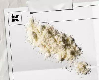 En haug med hvitt pulver på et blankt ark med en logo i hjørnet, som antyder en kunstnerisk eller stilistisk presentasjon.