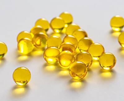 A collection of small, shiny yellow spheres scattered on a light background.