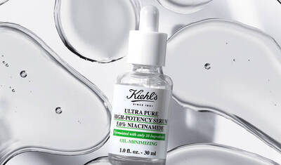 A bottle of Kiehl's Ultra Pure High-Potency Serum with 5% Niacinamide, displayed against a backdrop of smooth, transparent drops of serum. The bottle is clear with a white dropper and a label detailing its formulation.