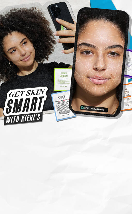 En kvinne med krøllete hår smiler mens hun holder en telefon som viser en ansiktsanalyse. I bakgrunnen er produkter fra Kiehl's og teksten "GET SKIN SMART WITH KIEHL'S".