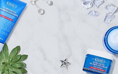 Produkter fra Kiehl's for hudpleie, inkludert rensegel, toner og ansiktskrem, omgitt av isbiter og sitron.