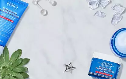 Bilde av ulike hudpleieprodukter fra Kiehl's, inkludert en ansiktsrens, toner og en krem, plassert på en marmoroverflate med isbiter og sitronskiver.
