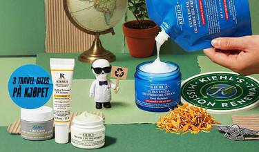 Hender som heller Kiehl's Ultra Facial Oil-Free Gel Cream med andre Kiehl's hudpleieprodukter, en globus, en plante og en liten figur på grønn bakgrunn.