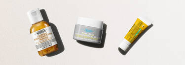 Tre hudpleieprodukter fra Kiehl's på en lys bakgrunn: Calendula-toner, Rare Earth-leirmaske og en liten gul tube.