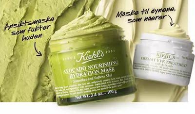 Close-up of two skincare products: a green jar labeled "Avocado Nourishing Hydration Mask" for smoothing and hydrating the skin, and a white jar labeled "Creamy Eye Treatment" for nourishing the eye area, set against a textured green backdrop.