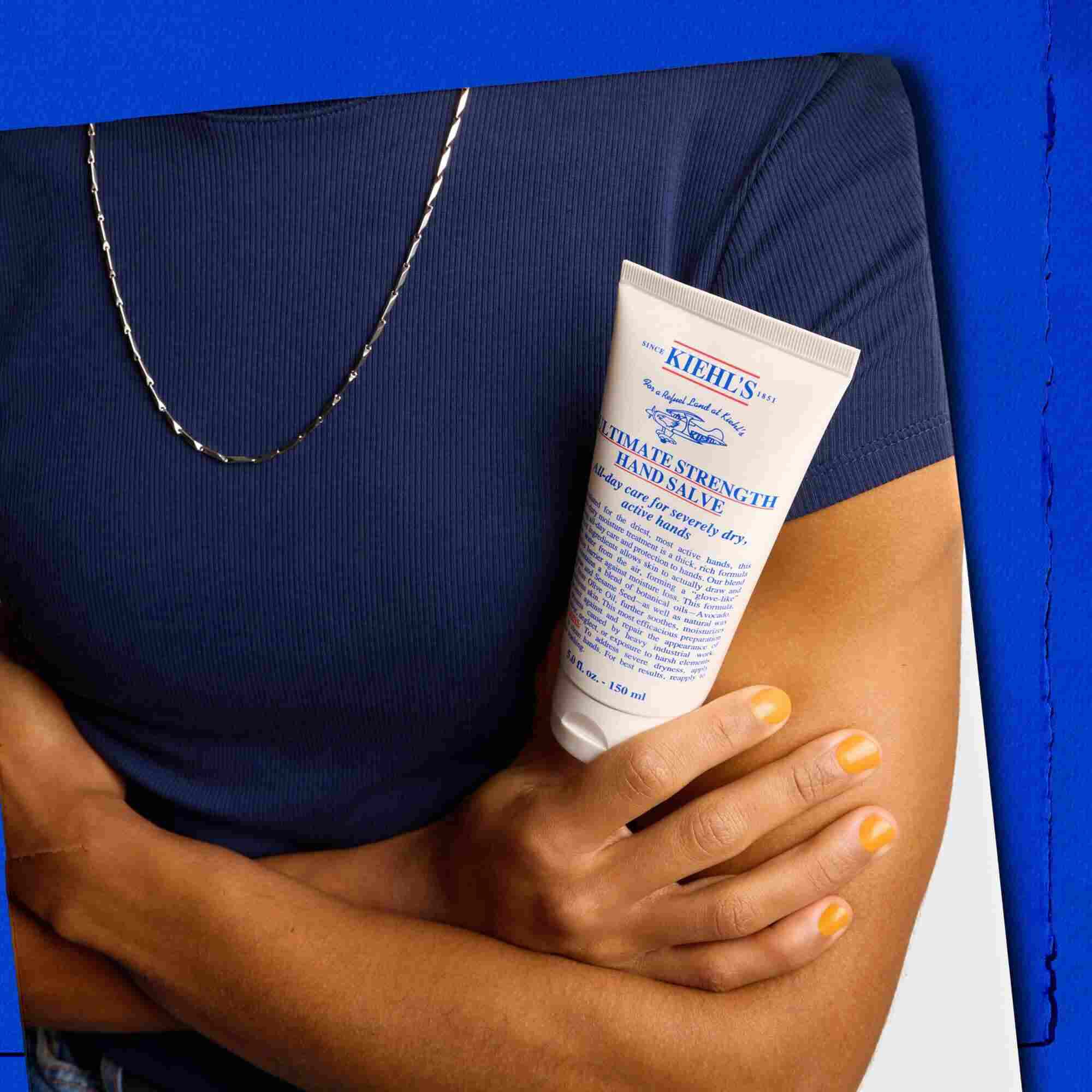 Modell som holder en tube med Kiehl's Ultimate Strength Hand Salve