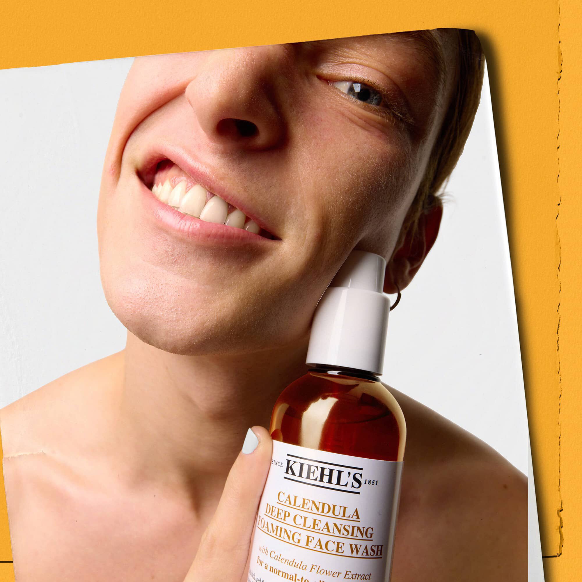 Modell som holder en flaske med Kiehl's Calendula Deep Cleaning Foaming Face Wash