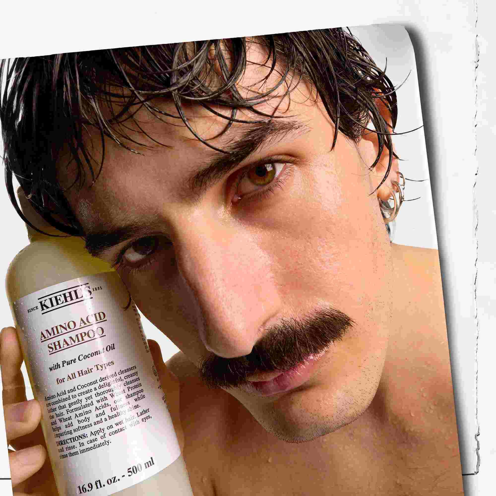 Modell med bart og en flaske Kiehl's Amino Acid Shampoo