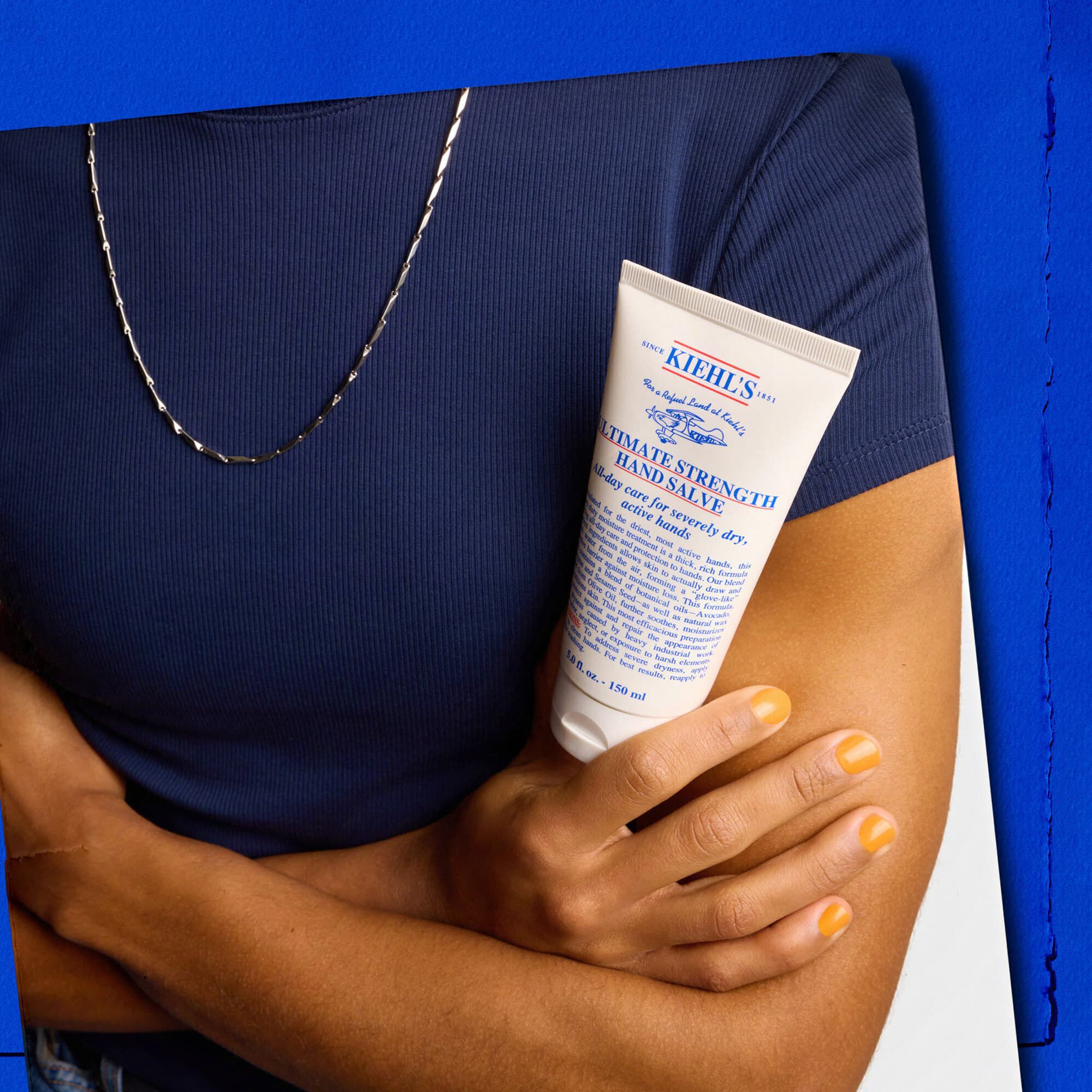 Modell som holder en tube med Kiehl's Ultimate Strength Hand Salve