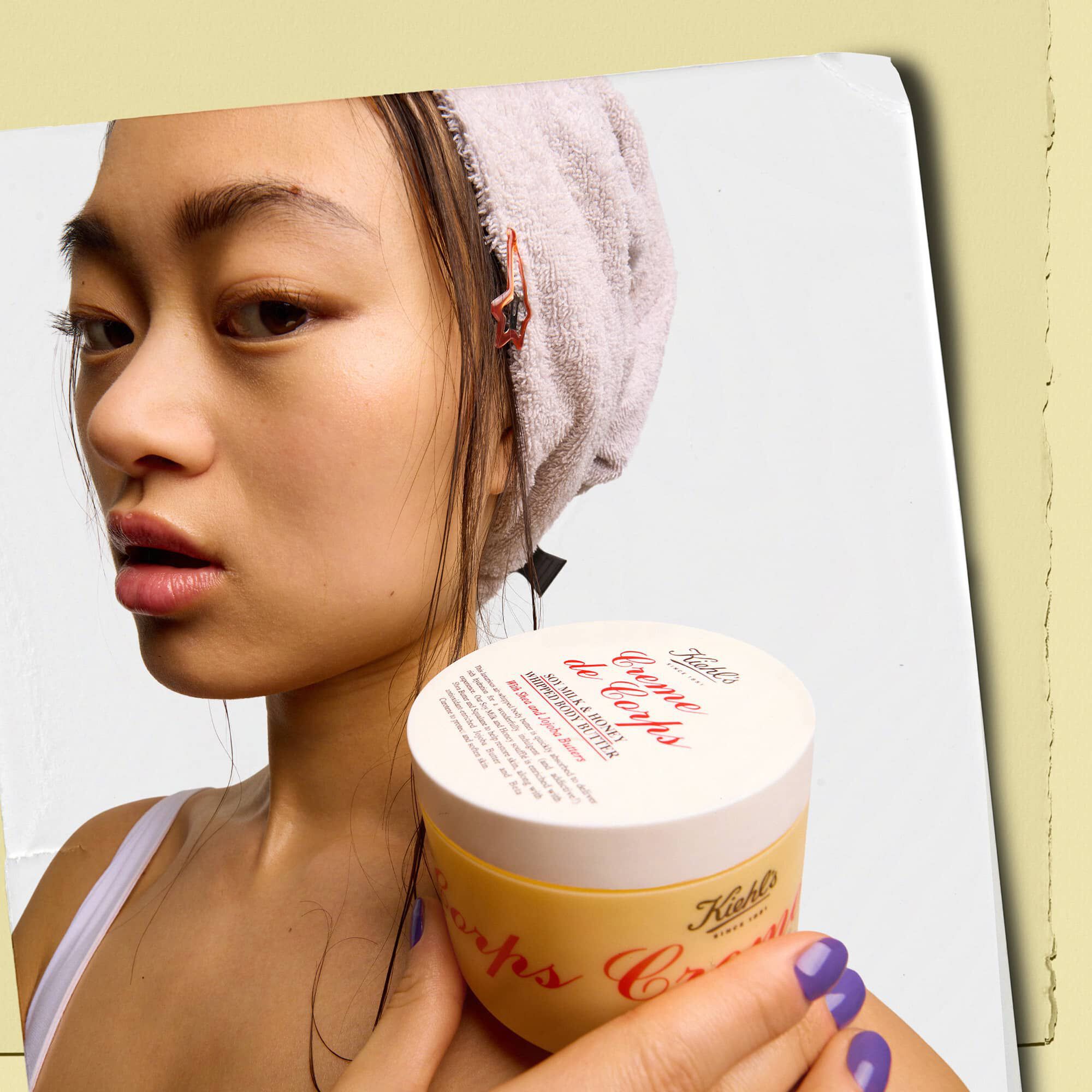 Modell som holder en krukke med Kiehl's Creme de Corps Whipped Butter bodybutter