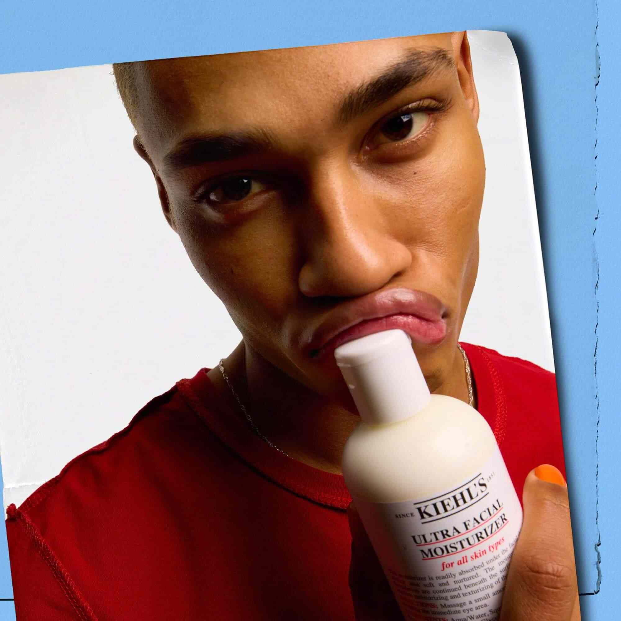 Modell som presser en flaske Kiehl's Ultra Facial Moisturizer mot leppene sine