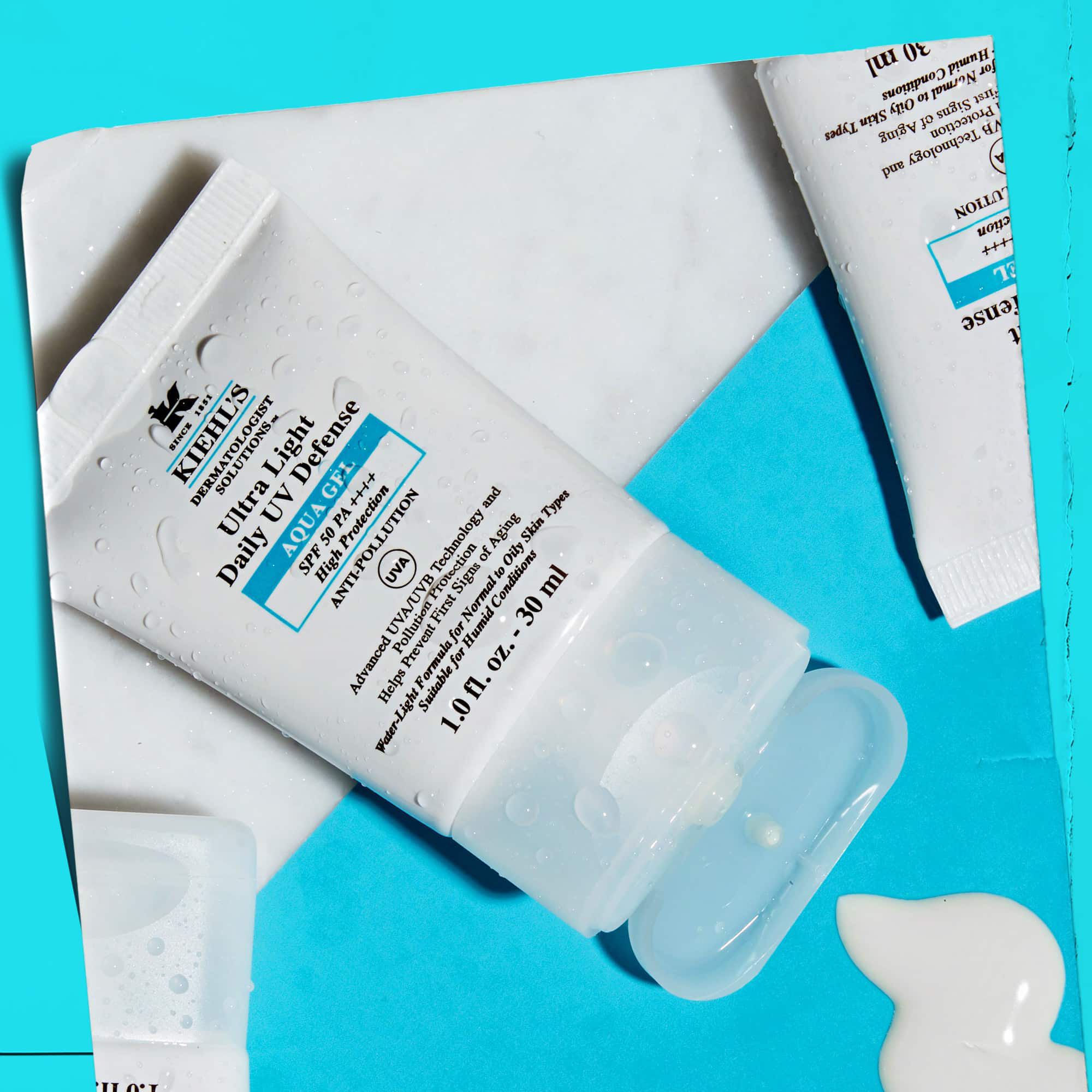 Et flat-lay av flere Ultra Light Daily UV Defense Aqua Gel-tuber på en marmoroverflate, som viser deres livsstilsappell.